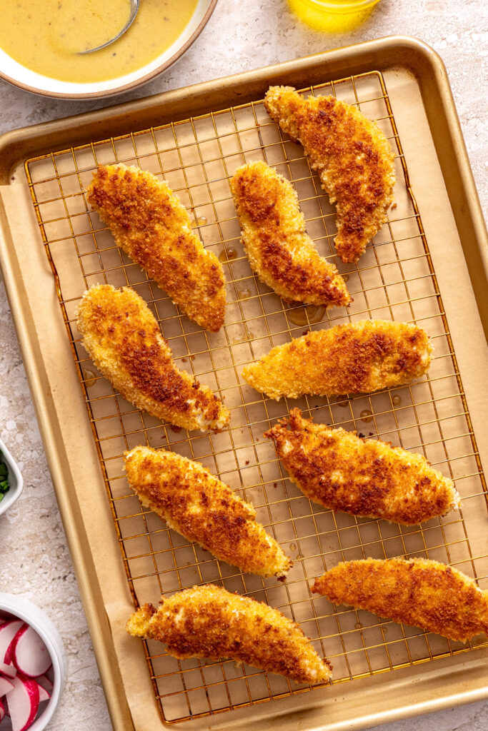 crispy chicken tenders on a wire rack over a parchment paper lined baking sheet