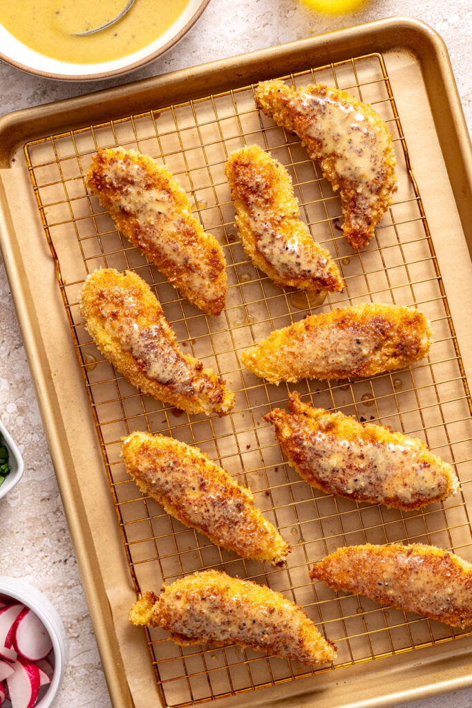 crispy chicken tenders brushed with homemade honey mustard dressing, cooling on a wire rack