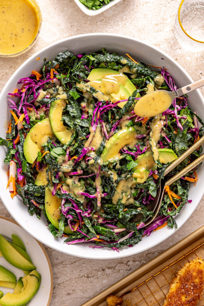 Mixing kale salad with carrots and radishes