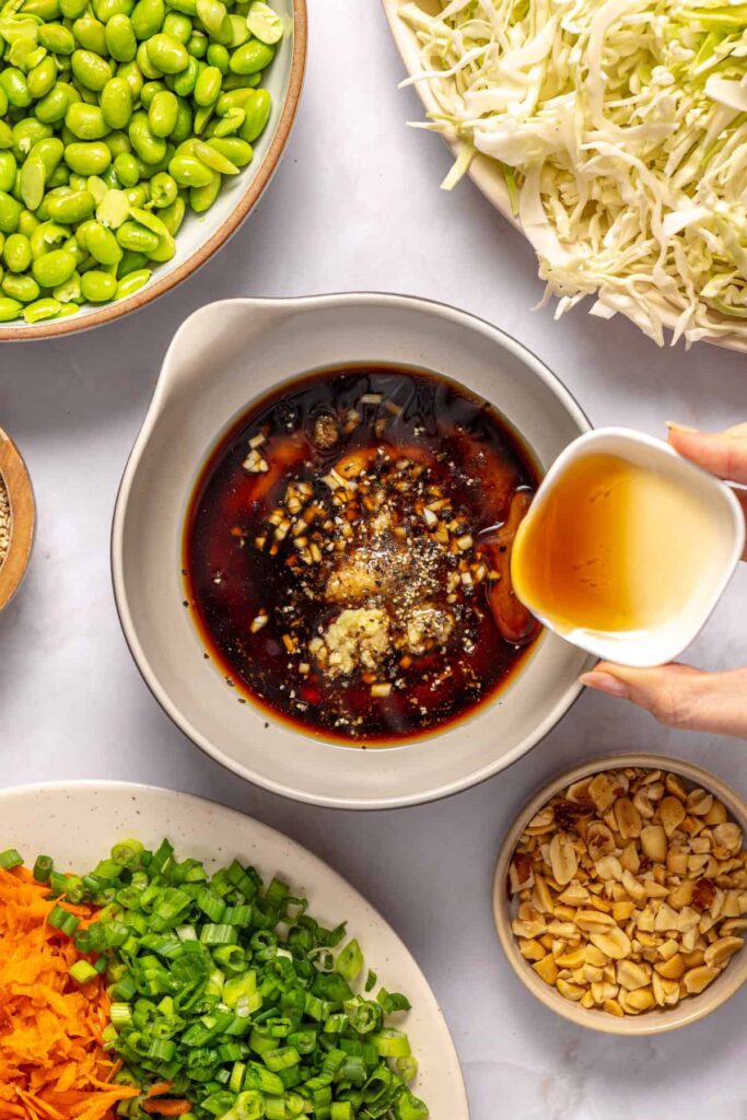 Adding peanut butter, sesame oil, rice vinegar, and lime juice to make peanut dressing for crunchy peanut cabbage salad