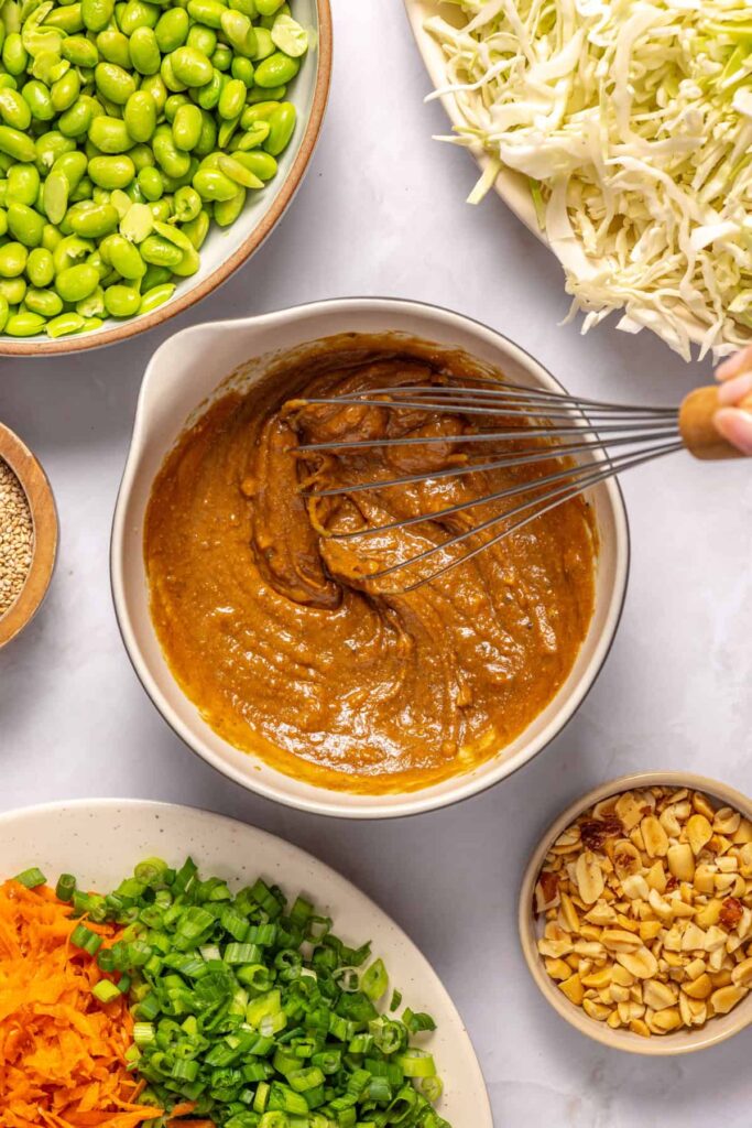 Whisking creamy peanut dressing until smooth for crunchy peanut cabbage salad