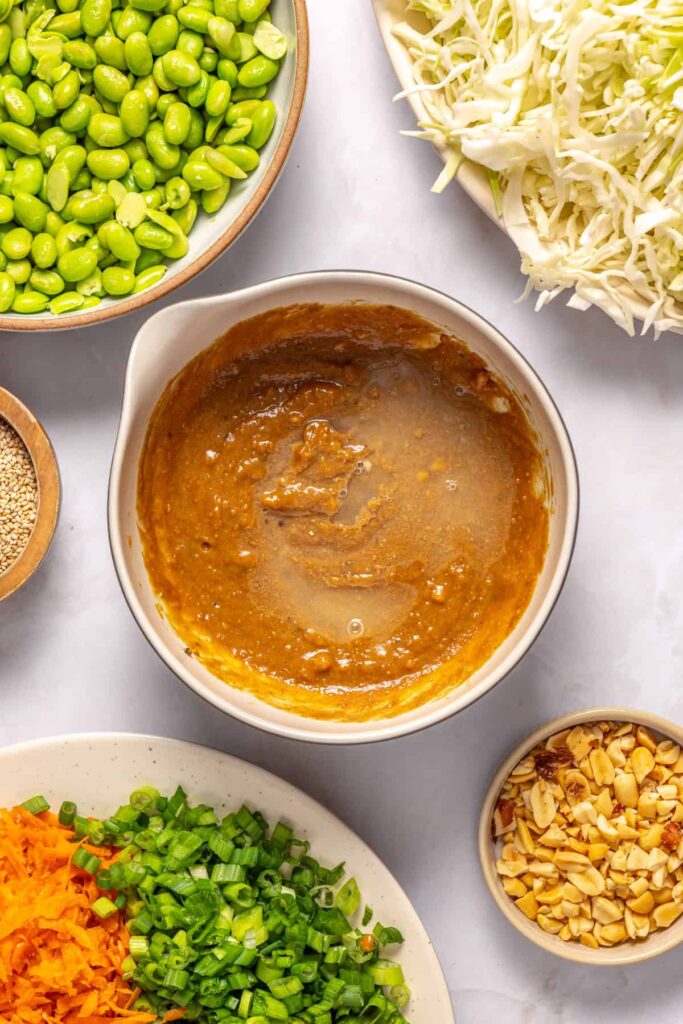 Adjusting peanut sesame dressing to desired consistency with warm water