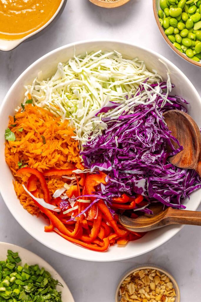 Thinly sliced cabbage, carrots, and bell pepper in mixing bowl for cabbage salad
