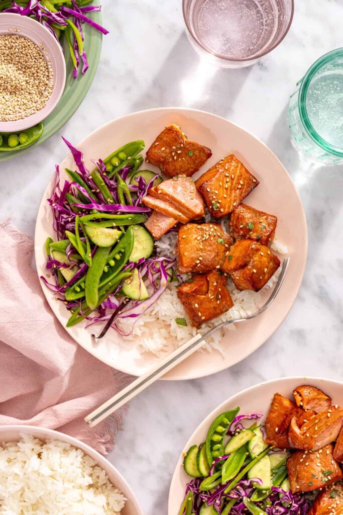 Overhead view of air fryer salmon bites with snap pea slaw and rice on a plate