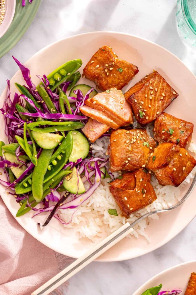 Close-up overhead of salmon bites with rice and snap pea slaw