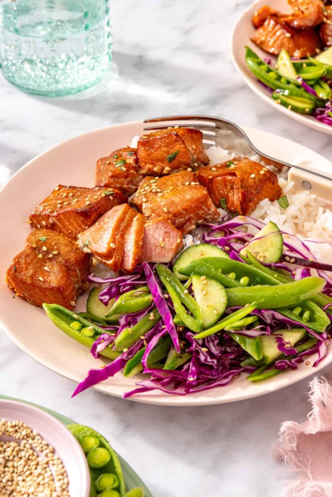Side angle of healthy salmon bites meal with fork and water glasses