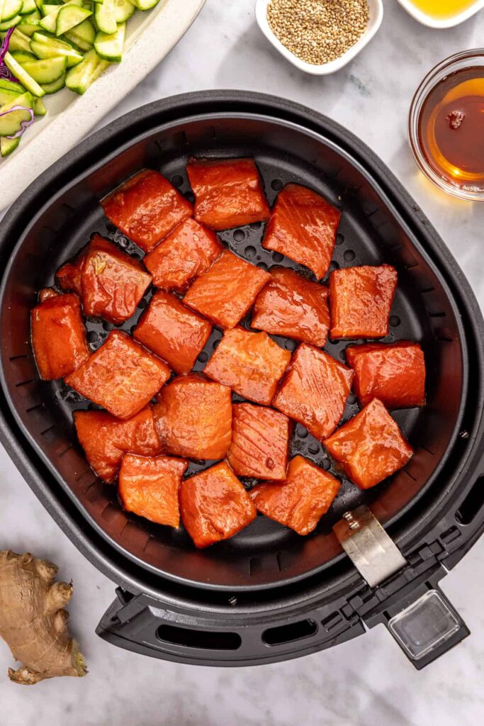 Salmon bites in air fryer basket ready to cook