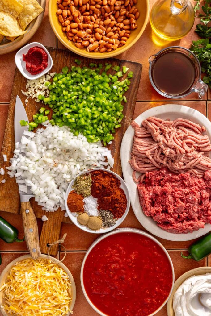 Overhead shot of ingredients for cheesy chili skillet with ground meat, beans, and spices