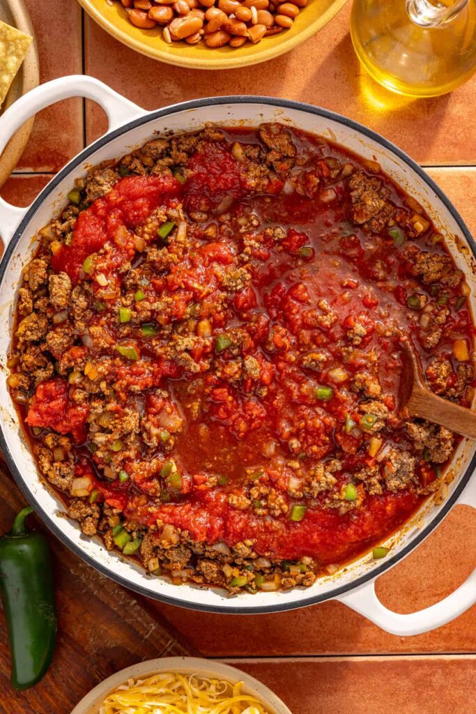 Chili simmering with beans, tomatoes, and broth in skillet