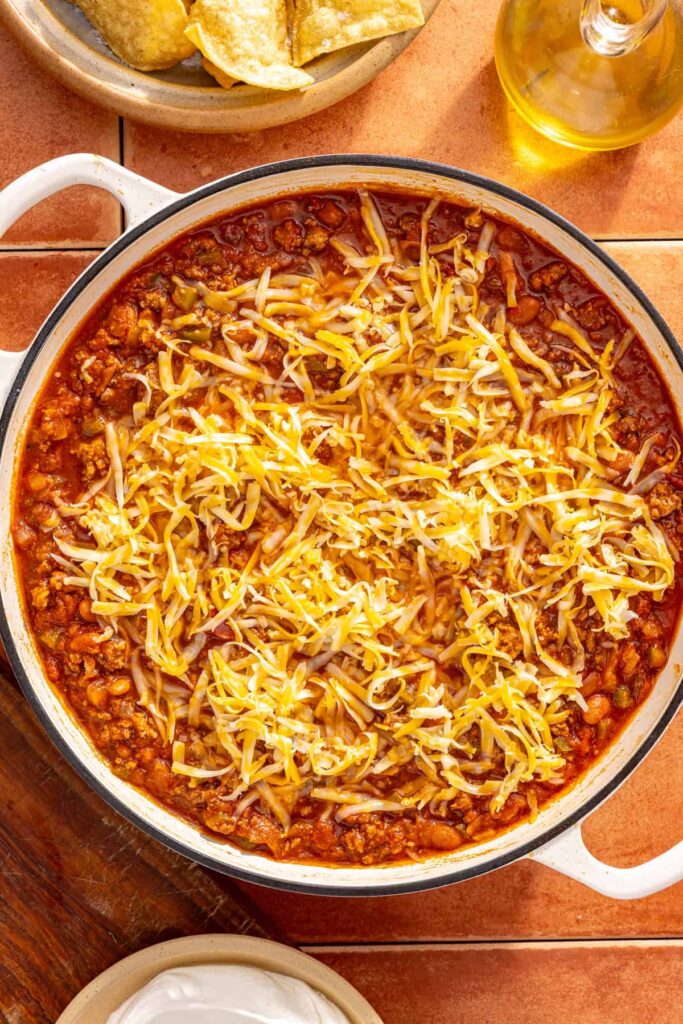 Shredded cheese sprinkled over chili skillet before broiling