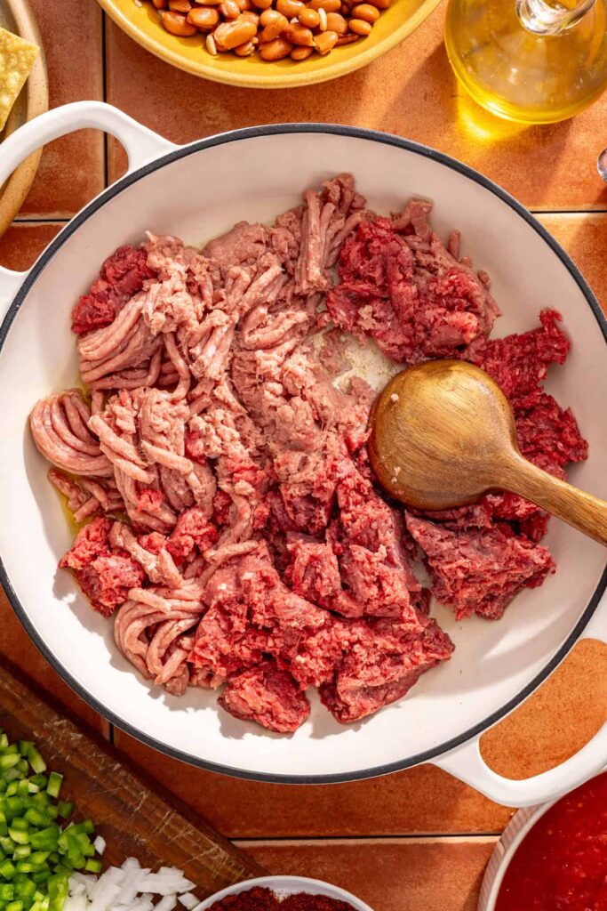 Cooking ground meat until browned for cheesy chili skillet