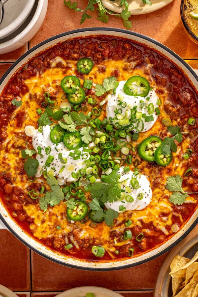 Chili skillet served family-style with toppings on a styled table