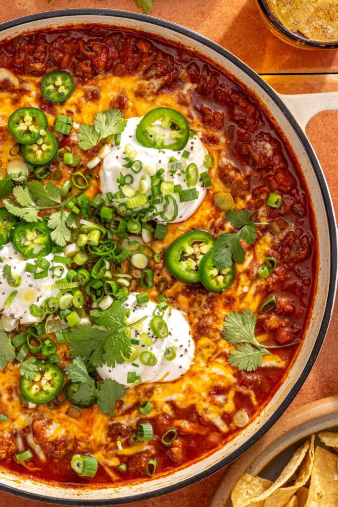 High-protein cheesy chili skillet with fresh garnishes ready to serve