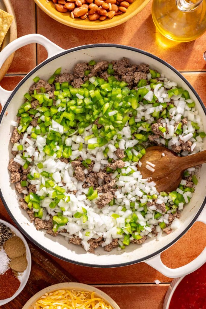 Diced onion and bell pepper cooking with meat in chili skillet