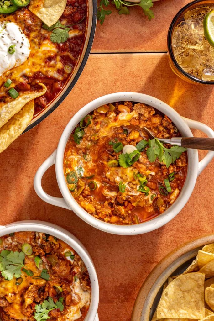 Cheesy chili skillet served in bowls with toppings and chips