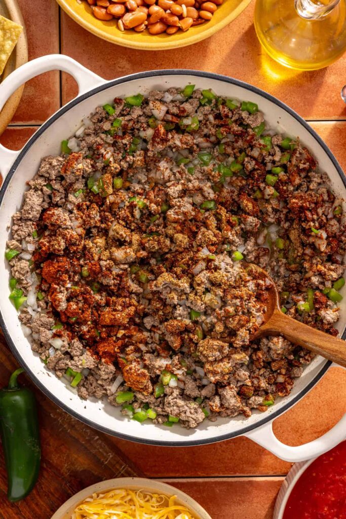 Spices added to chili skillet including chili powder and cumin