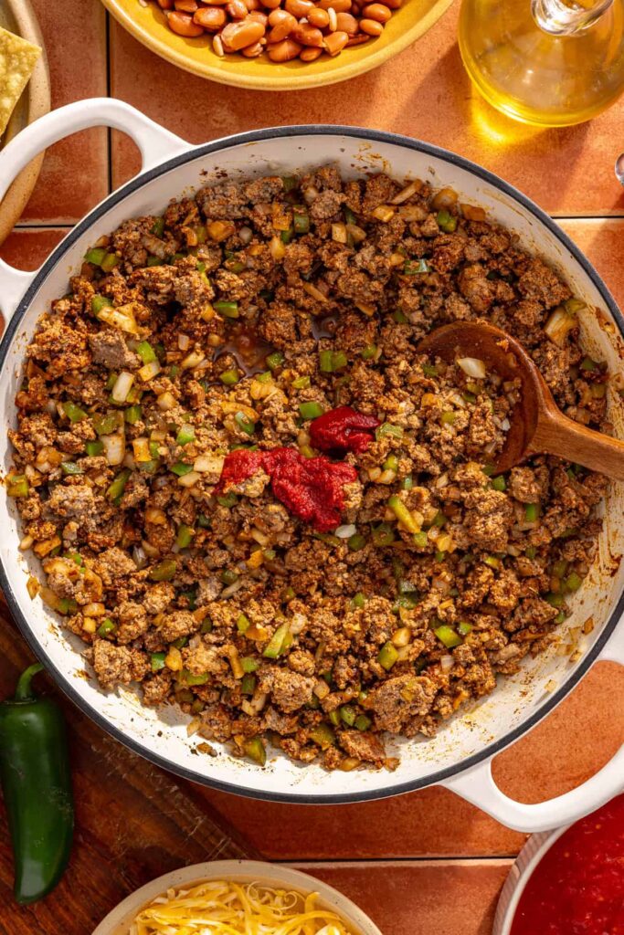 Tomato paste mixed into chili skillet to deepen flavor