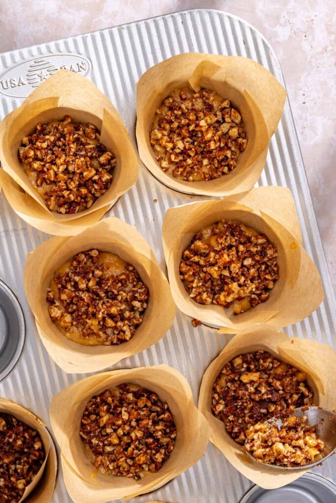 Sprinkling streusel topping into muffin cups to create coffee cake swirl