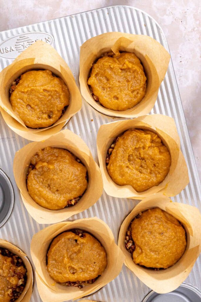 Filling muffin tin with coffee cake muffin batter