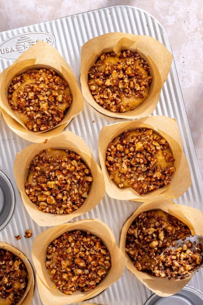 Topping muffin batter with cinnamon streusel before baking coffee cake muffins