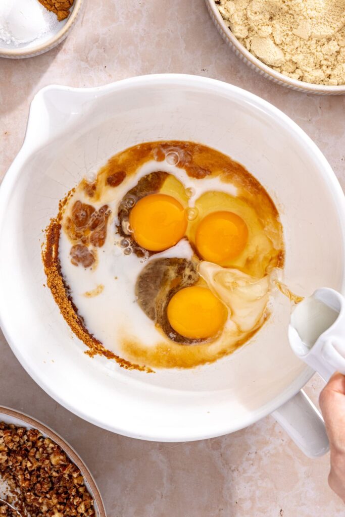 Mixing wet ingredients for gluten-free coffee cake muffins in a large bowl