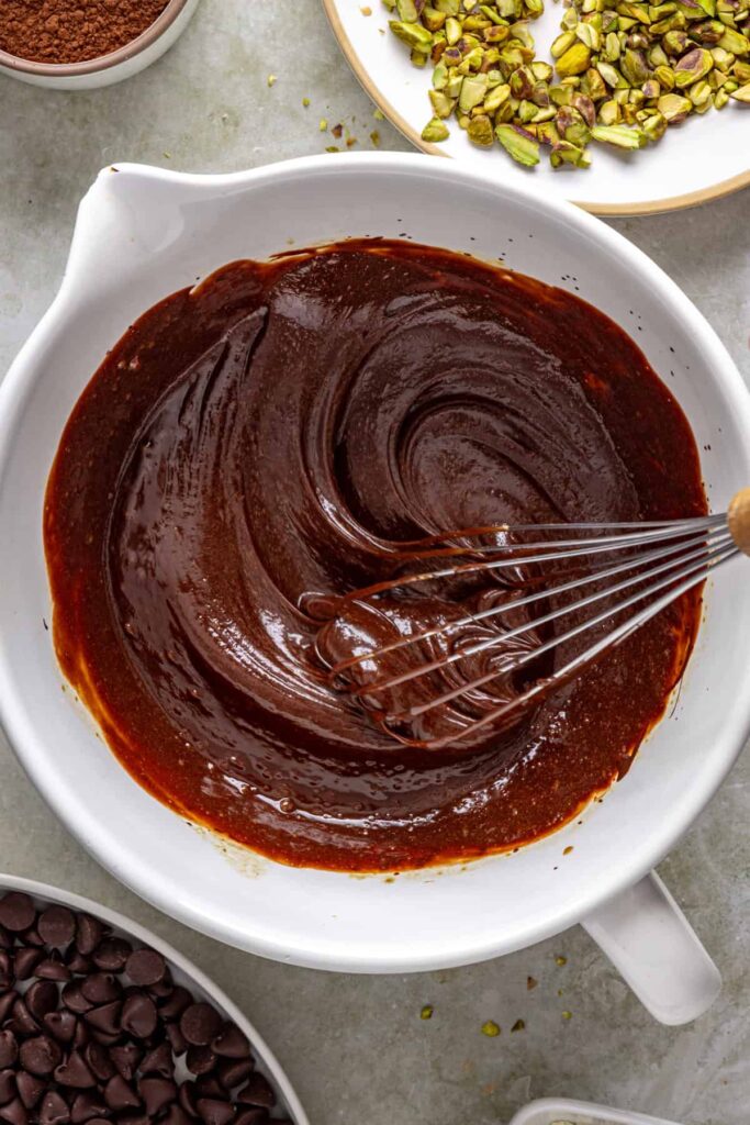 Chocolate brownie batter being whisked smooth in mixing bowl