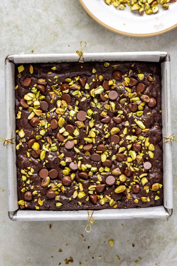 Freshly baked pistachio brownies in pan with chocolate chips on top