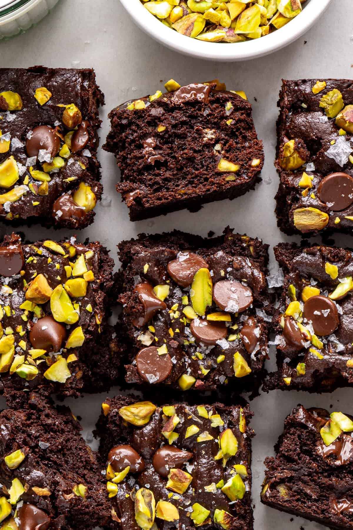 overhead shot of gluten-free pistachio brownies styled with bowl of chopped pistachios