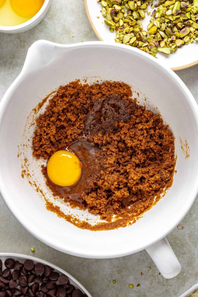 Adding eggs to chocolate brownie batter for fudgy pistachio brownies