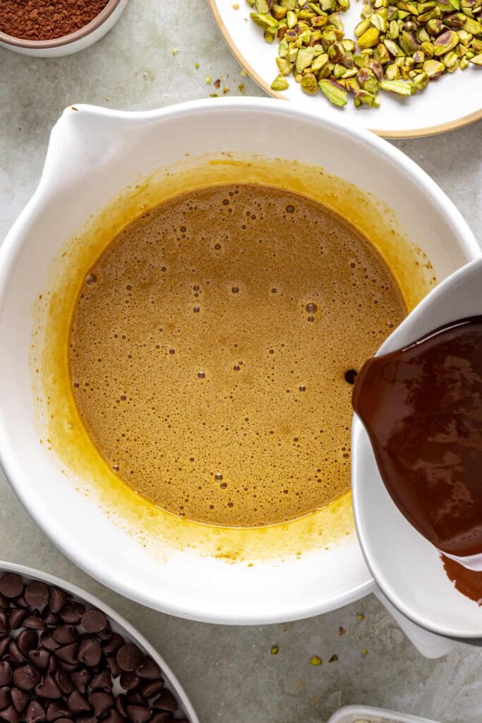 pouring melted dark chocolate into egg mixture for fudgy brownies