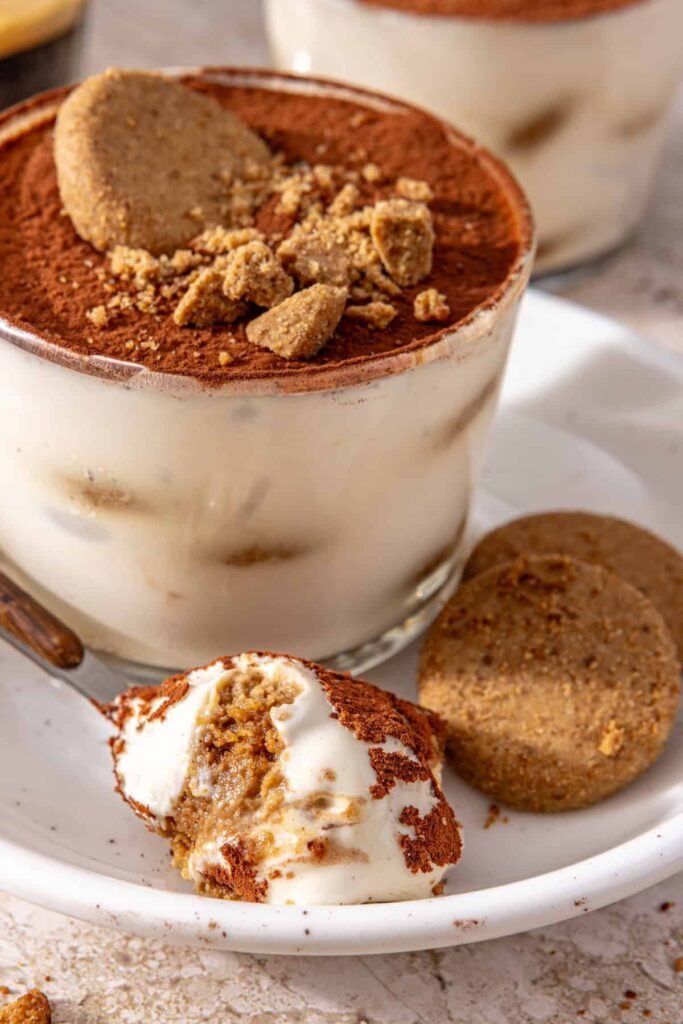 Spoonful of high-protein tiramisu on plate with cookies