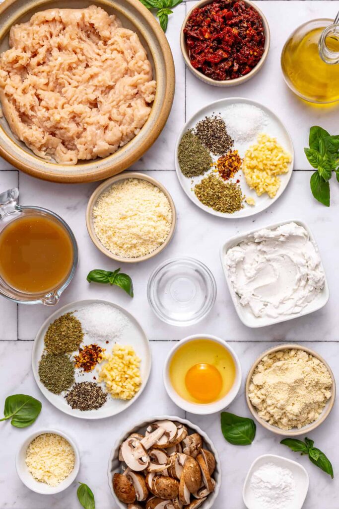 Marry me chicken meatballs ingredients arranged on counter including ground chicken, coconut cream, sun-dried tomatoes, and herbs