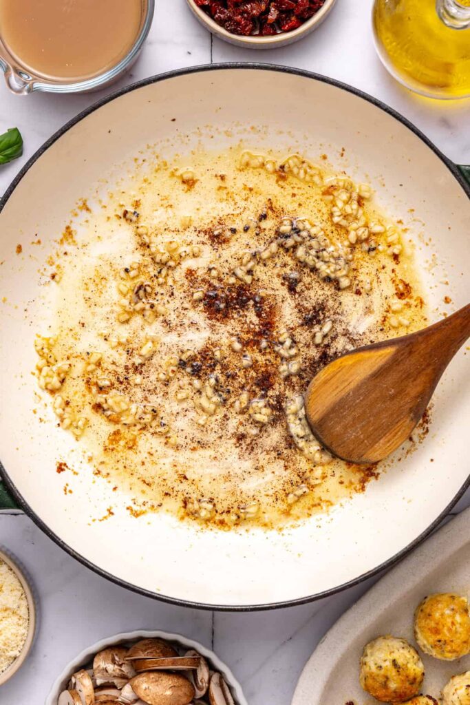 Cooking minced garlic in skillet for marry me chicken meatballs sauce