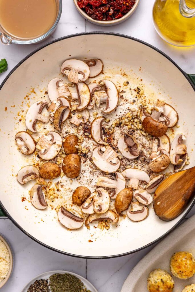 Cooking sliced mushrooms in skillet for creamy chicken meatball recipe