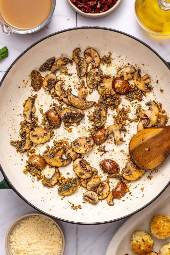 Blooming oregano and thyme in pan for creamy chicken meatball sauce