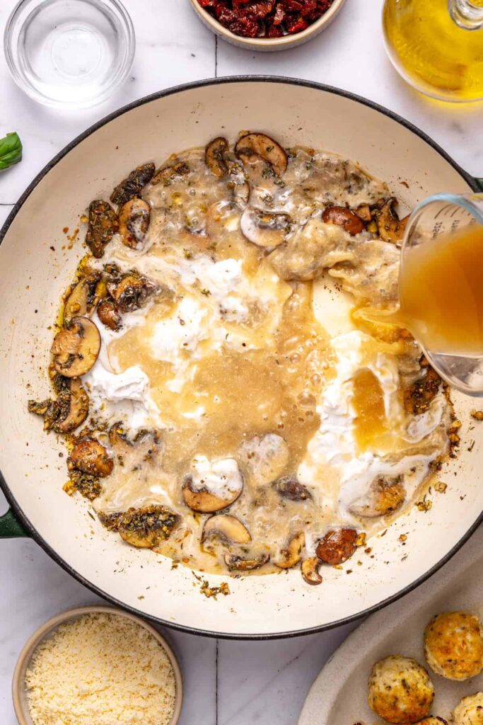 Pouring coconut cream and broth into skillet for marry me chicken meatballs