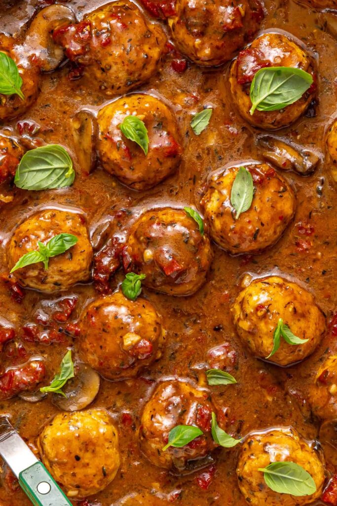 close-up of Marry me chicken meatballs with basil garnish in creamy sauce