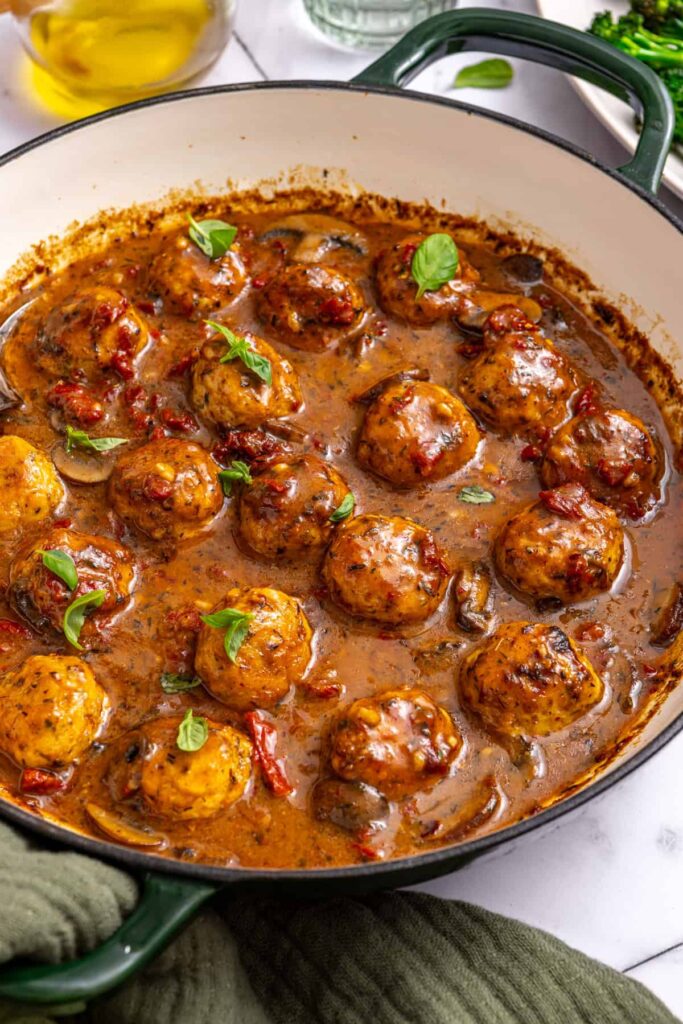 side angle of one pan chicken meatballs in a creamy sauce on a set table