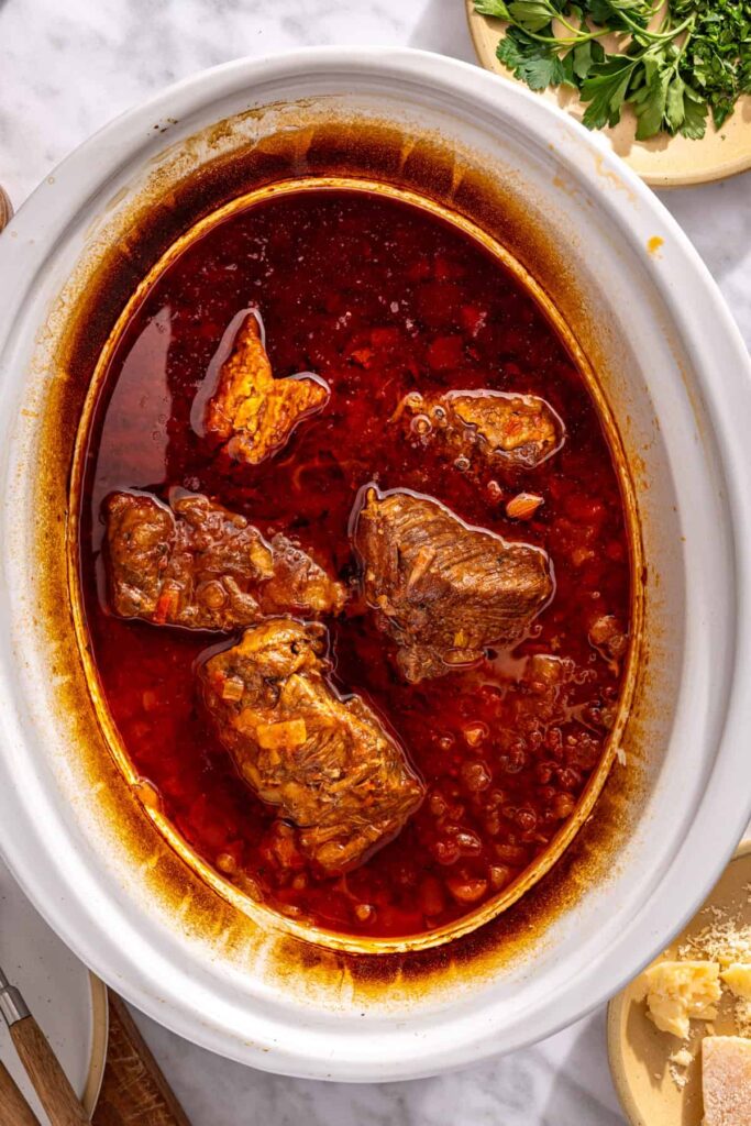 Tender beef ragu ready to be shredded in slow cooker