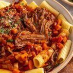 Close-up of slow cooker short rib ragu over pasta with rich tomato sauce