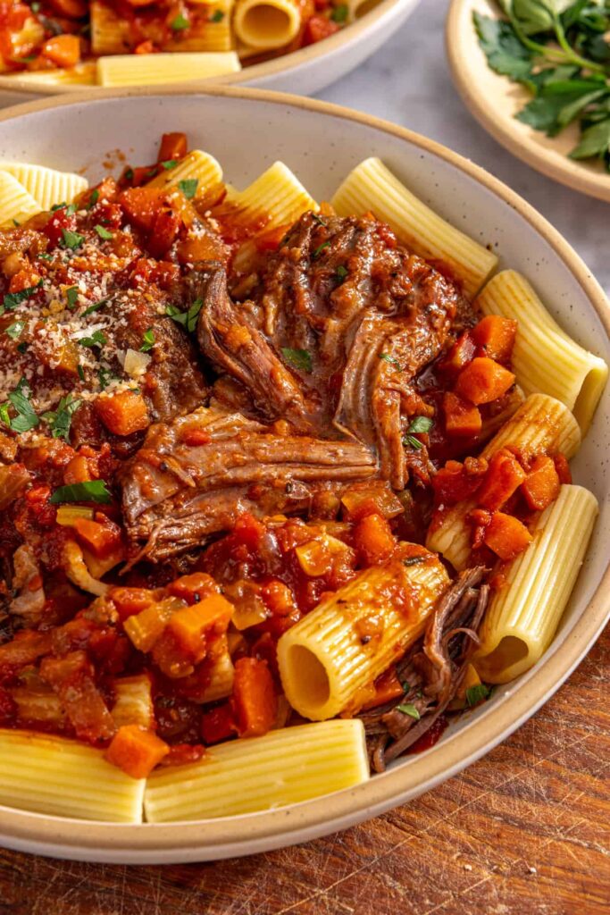 Close-up of slow cooker short rib ragu over pasta with rich tomato sauce