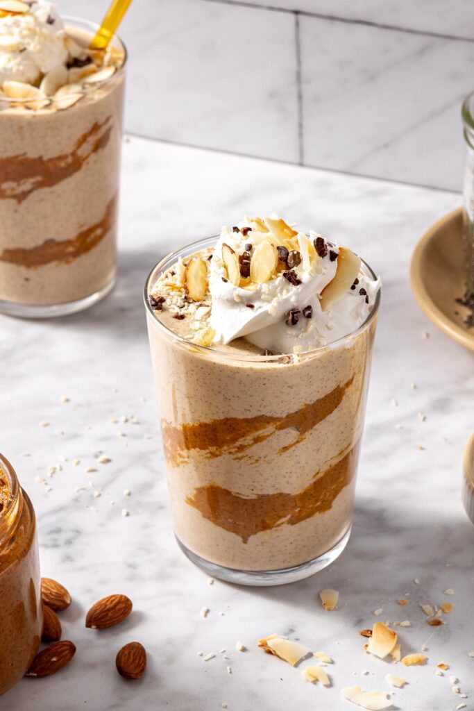 Almond joy healthy dessert smoothie garnished with chocolate and coconut, served in glass