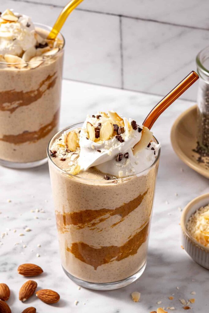 Healthy dessert smoothie in glass with straw and chocolate coconut toppings