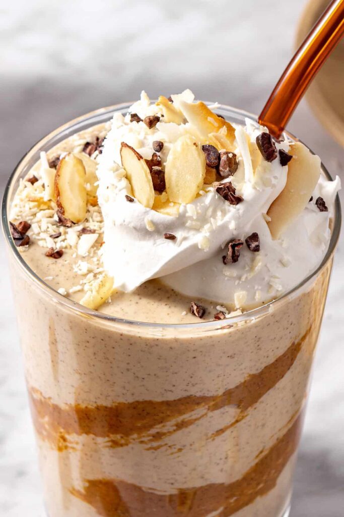 Thick vegan healthy dessert smoothie served with straw and garnish