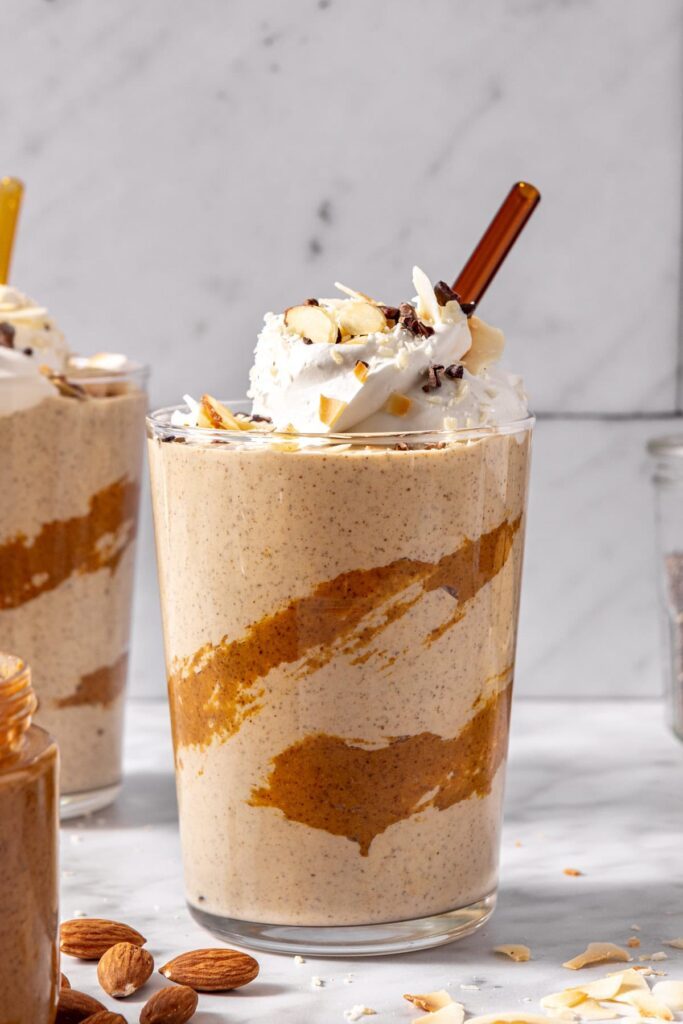 coconut milk smoothie with toppings and drizzled almond butter in a glass