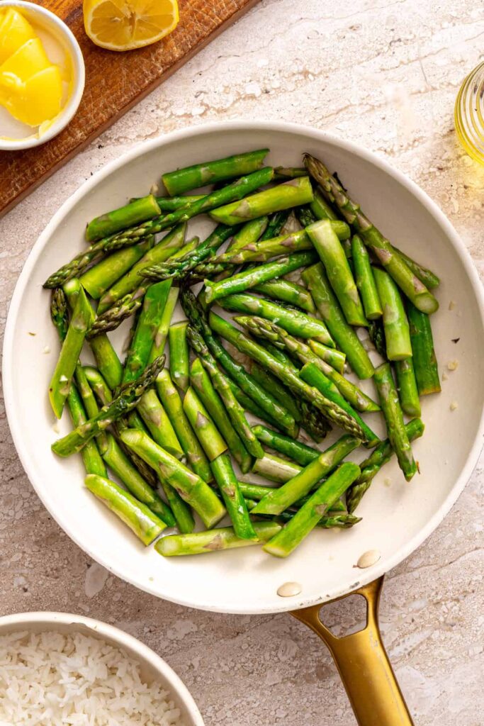 Sautéing asparagus with garlic in skillet