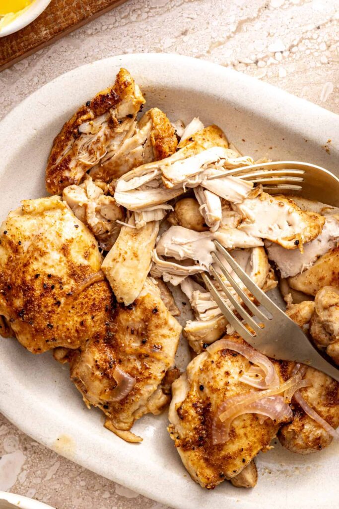 Shredding cooked chicken thighs with two forks