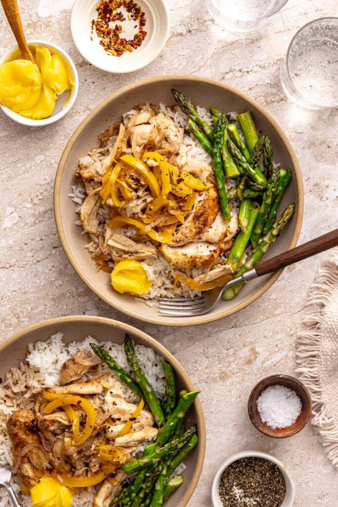Overhead chicken thigh rice bowls on styled table with spices and ghee