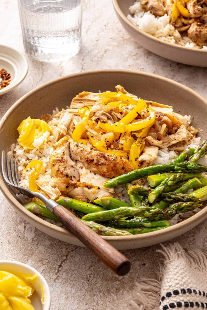 Side view of chicken thigh rice bowl with asparagus and peppers
