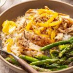 Cozy chicken thigh rice bowls with shredded chicken, asparagus, peppers and jasmine rice topped with ghee, close-up side angle